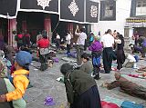 
We watched the devout pilgrims prostrate themselves at the Jokhang Temple’s entrance doors. Their hands are protected by large mittens or small block of wood fixed to the waist by a lace. People kneel, their hands reach the ground and they start sliding until the whole body extends on the ground too. Standing up they then repeat the action again and again.
